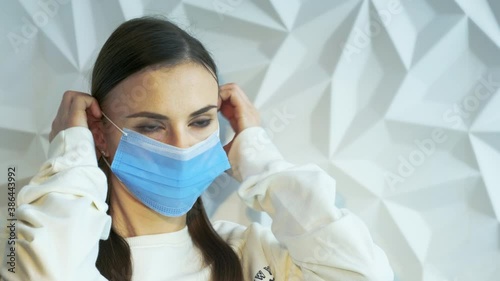 A beautiful brunette girl in white as a doctor puts on a mask, showing safety from a viral pandemic, this is safety from covid, and will stop lockdown, against a white volumetric background