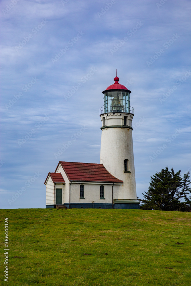 red and white lighthouse on a grassy hill