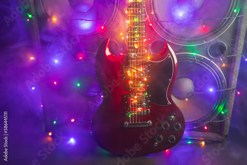 abstract guitar with festive Christmas lights and music speakers in smoke