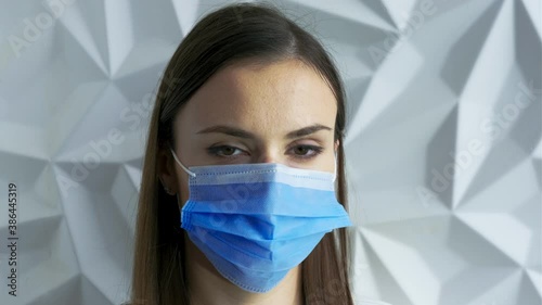 A beautiful brunette girl in white as a doctor puts on a mask, showing safety from a viral pandemic, this is safety from covid, and will stop lockdown, against a white volumetric background