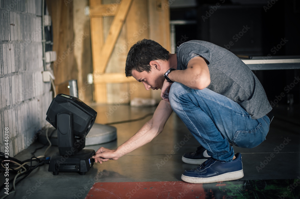 Theater lighting technician electric engineer adjusting focus of lighting elements backstage. Spotlights in the theater. Behind the scene Theater lighting technician electric engineer adjusting focus of lighting elements backstage. Spotlights in the theater. Behind the scene