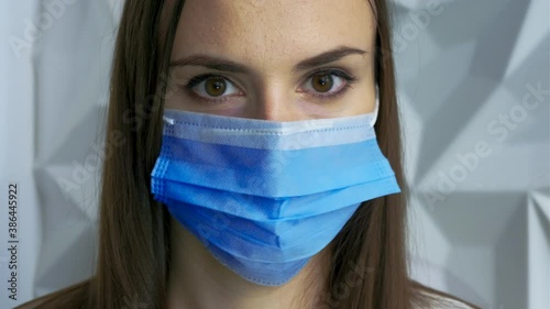 A beautiful brunette girl in white as a doctor puts on a mask, showing safety from a viral pandemic, this is safety from covid, and will stop lockdown, against a white volumetric background