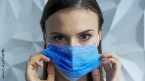 A beautiful brunette girl in white as a doctor puts on a mask, showing safety from a viral pandemic, this is safety from covid, and will stop lockdown, against a white volumetric background