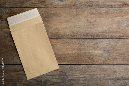 Kraft paper envelope on wooden background, top view. Space for text