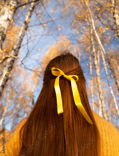 back of a red-haired girl in the autumn forest