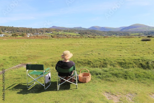 A female having a picnic and enjoying the view of the Rhinog mountains from Llandanwg, Wales, UK. © Wendy