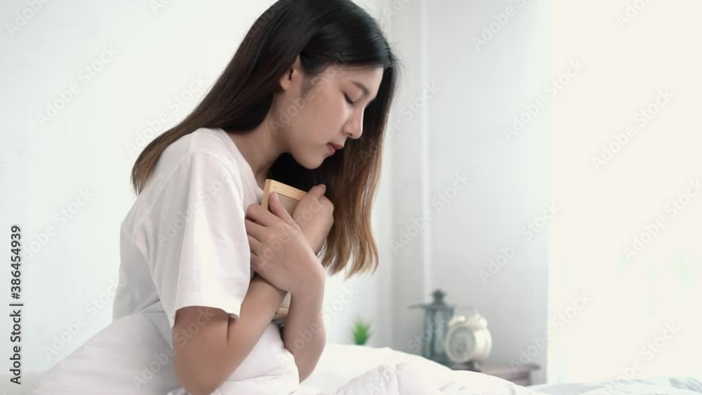 Sad Asian woman with a photo in hands looking thoughtfully Sad Asian woman with a photo in hands looking thoughtfully