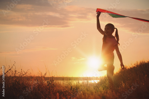 Cute little child with kite running outdoors at sunset. Spending time in nature