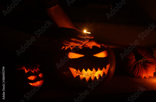Hand putting a candle into a jack O'lantern halloween pumpkin at night