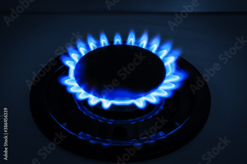Gas burner of modern stove with burning blue flame at night © New Africa