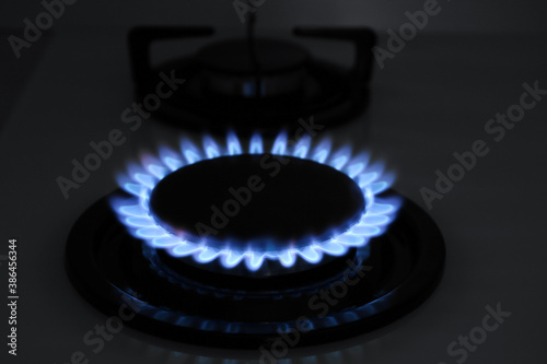 Modern gas cooktop with burning blue flame in kitchen at night © New Africa