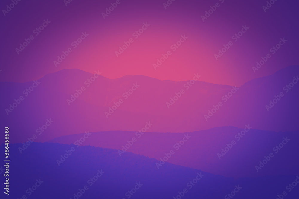 Vibrant and colorful purple sunset with silhouette of mountain