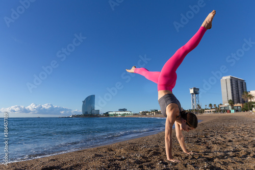 Caucasian woman doing stretching and yoga on Barceloneta beach in Barcelona photo