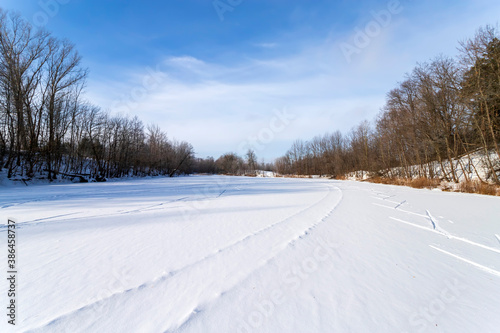 Sun, snow and Ski track crossing a frozen lake. Winter sport.