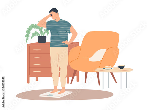 Man at home stands on the scales and looks at them puzzled. He gained extra weight.