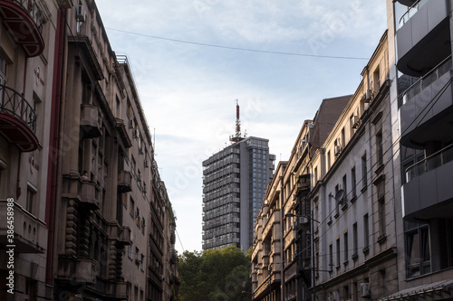 Old residential buildings made of concrete and a 70s high rise steel skyscraper in the city center of Belgrade, the capital city of Serbia, during a sunny afternoon