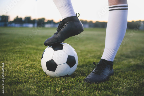 Legs of a female soccer or football player on ball at stadium, close up