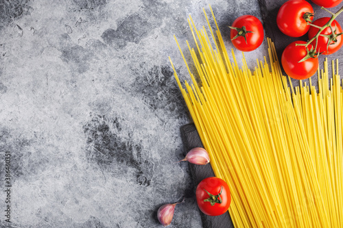 spaghetti pasta, red tomatoes, garlic and herbs on the table