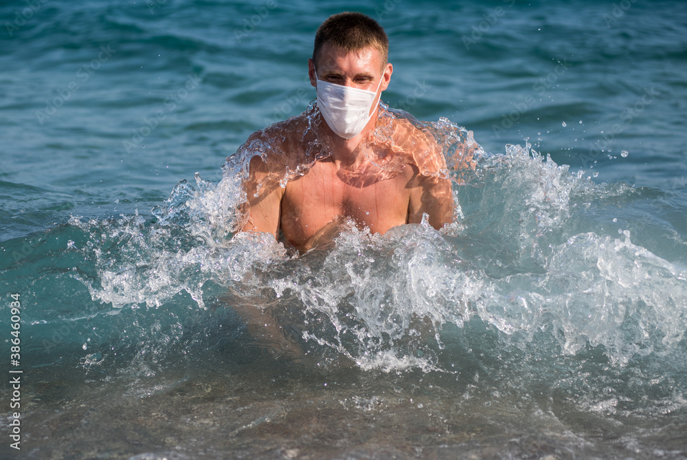 a man splashes alone in the open sea wearing a mask during the covid 19 flu epidemic