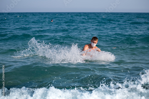 a man splashes alone in the open sea wearing a mask during the covid 19 flu epidemic © Konstantin Ivshin