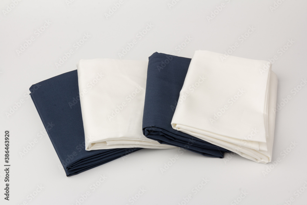 Stack of clean white and blue bed sheets on white background, closeup. Stack of clean white and blue bed sheets on white background, closeup.