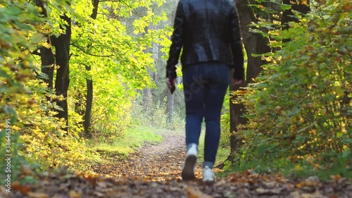 a girl in white sneakers walks through the fallen leaves. rear view. autumn in the Park.