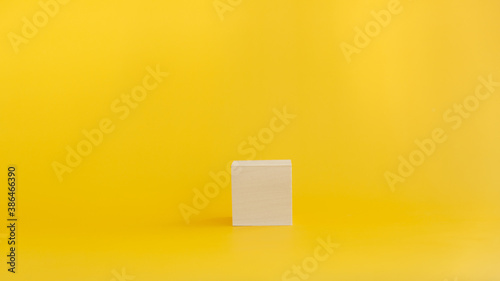White wooden empty cube on a yellow background