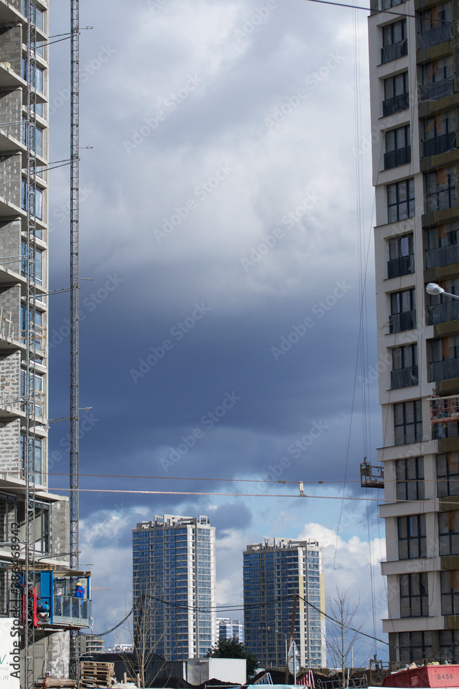 Construction of modern multi-storey buildings. New development of a residential area. House frames, construction cranes and building materials at the construction site.