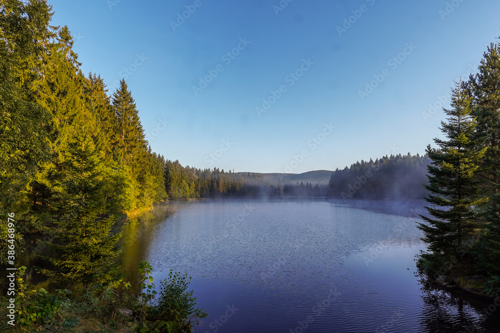 Ein See im Nebel am Morgen mit Sonnenstrahlen Fichtelsee Fichtelgebirge