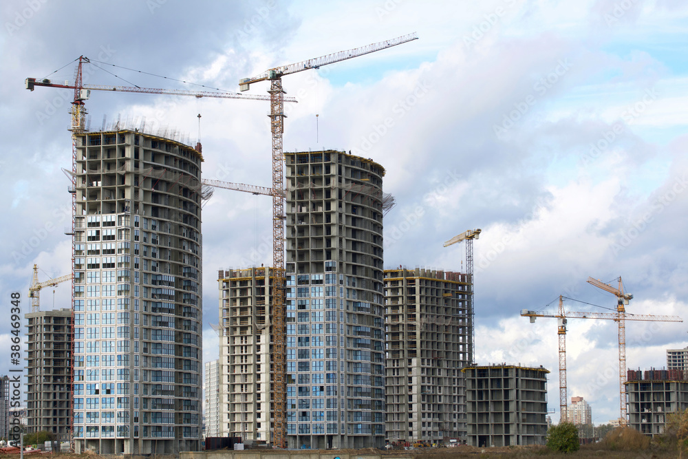 Construction of modern multi-storey buildings. New development of a residential area. House frames, construction cranes and building materials at the construction site. Construction of modern multi-storey buildings. New development of a residential area. House frames, construction cranes and building materials at the construction site.