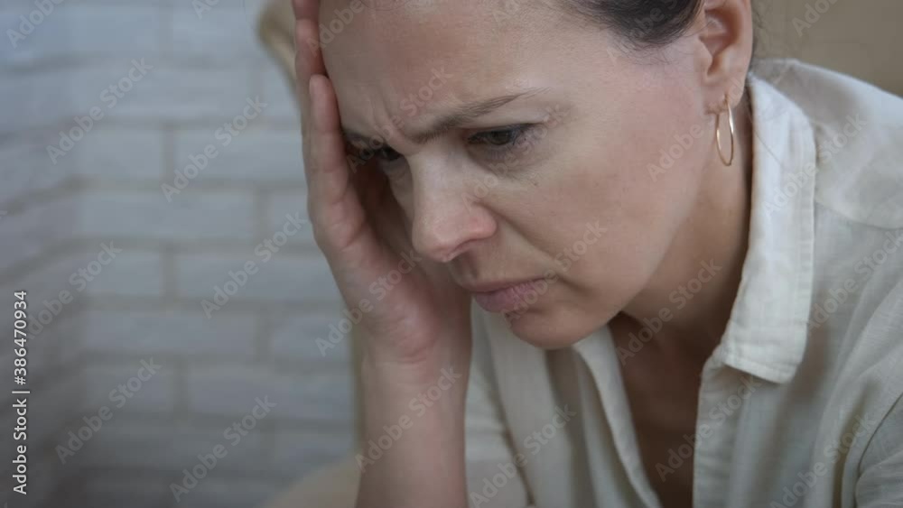 Feel anxiety problem. A view of a pensive woman feeling anxiety problem sitting on the sofa in the room. Feel anxiety problem. A view of a pensive woman feeling anxiety problem sitting on the sofa in the room.