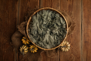 Prop digital background of newborn photography.  wooden basket with green fur and decorated with small pumpkins on a wooden background.