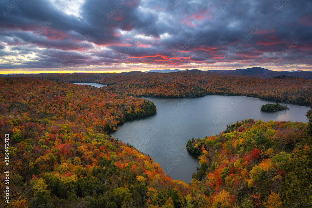 Colorful storm clouds over Nichols Pond surrounded by beautiful autumn colors in Vermont 