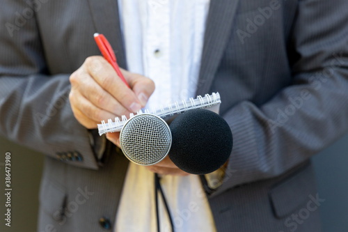 Correspondent or reporter at media event, holding microphone, writing notes. Journalism concept. photo