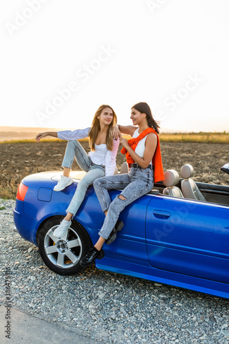 Young two women sitting on convertible car and talking spend free time together. © F8  \ Suport Ukraine