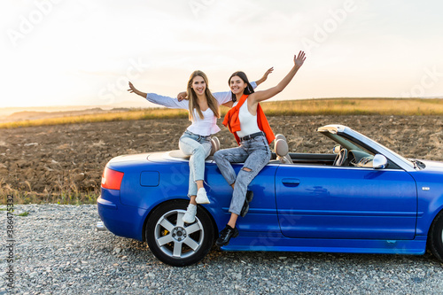Two happy women friends taking selfie when road trip in convertible car.