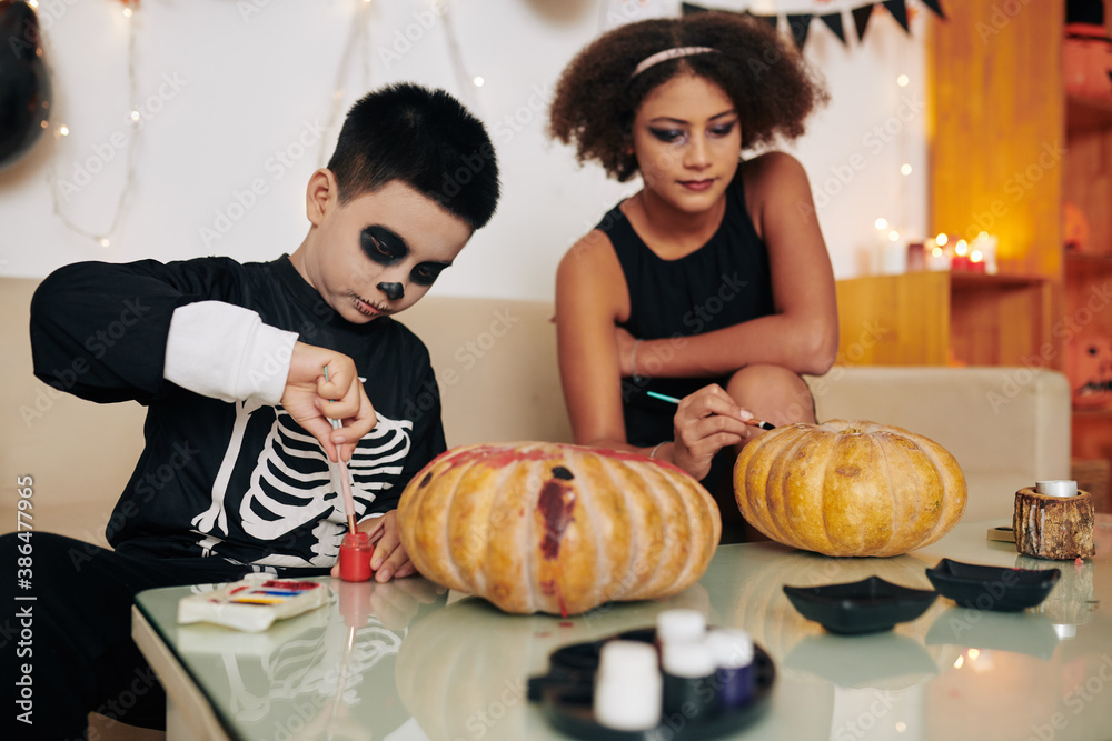 Children painting carved pumpkins for Halloween celebration