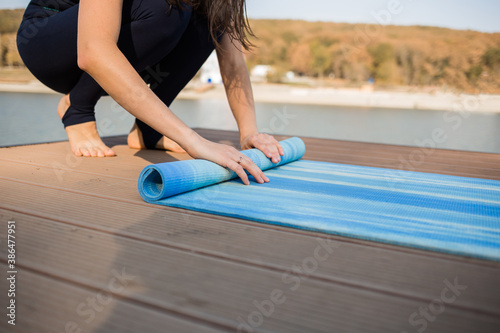 close-up of a yoga woman rolling up a blue yoga Mat
