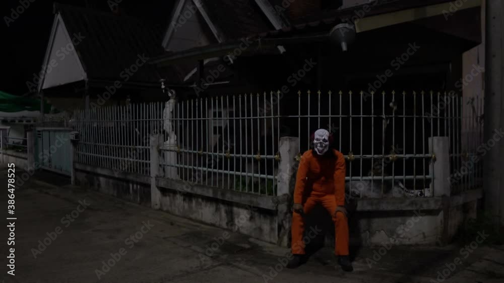 Asian handsome man wear clown mask with weapon at the night scene,Halloween festival concept,Horror scary photo of a killer in orange cloth Asian handsome man wear clown mask with weapon at the night scene,Halloween festival concept,Horror scary photo of a killer in orange cloth