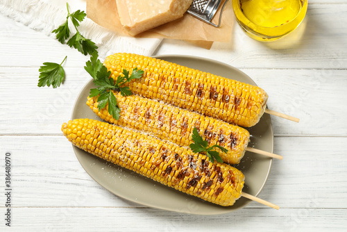 Tasty grilled corn on white wooden table, flat lay photo