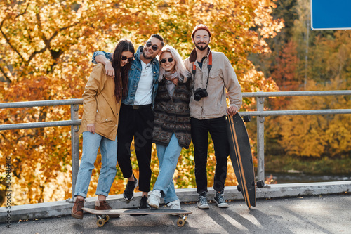 Fotografía Carefree and well dressed company of two guys and two girls having a good time and photographing in autumn background