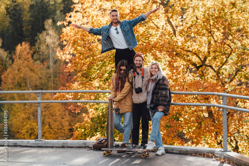 Four joyful friends one of them showing he is flying having a good time spending their holidays together in auturm park in daytime. photo