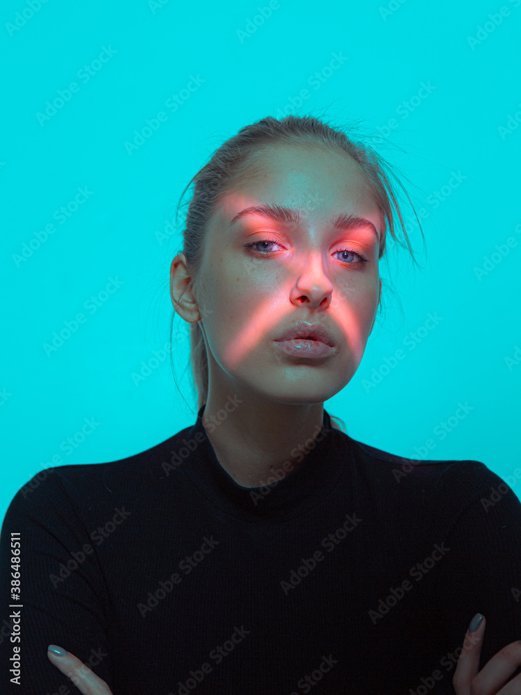 Mysterious portrait of young pretty girl with cross shaped red neon light on face Mysterious portrait of young pretty girl with cross shaped red neon light on face