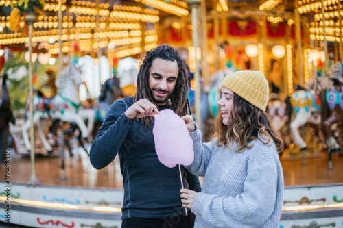 Young couple eating cotton candy at a Christmas fair