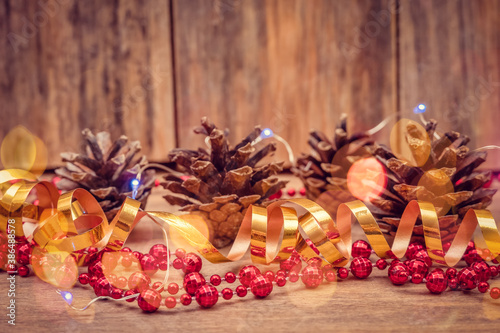 Holiday, Christmas composition of cones, red beads, gold ribbon and blue lights on a wooden background with copy space. Beautiful Christmas background