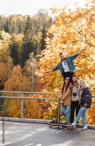 Four joyful friends one of them showing he is flying having a good time spending their holidays together in auturm park in daytime. photo