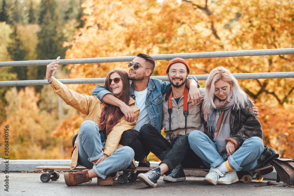 Peaceful autumn park and group of two boys and two girls they are relaxing and photographing on skates in daytime. Peaceful autumn park and group of two boys and two girls they are relaxing and photographing on skates in daytime.