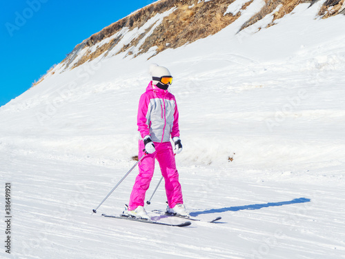 A skier in a pink suit rides a straight track on a clear winter day