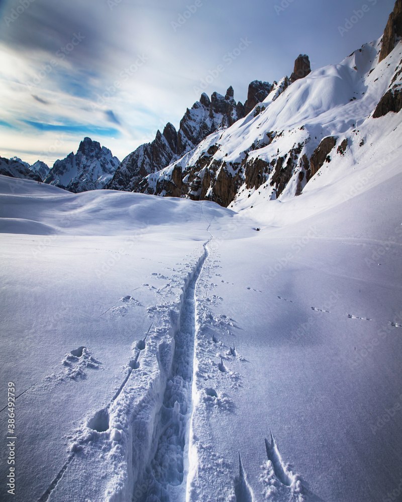 Winter landscape with traces of a skier, hike on snowshoes in the Alps. Dolomites, South Tyrol, Italy.