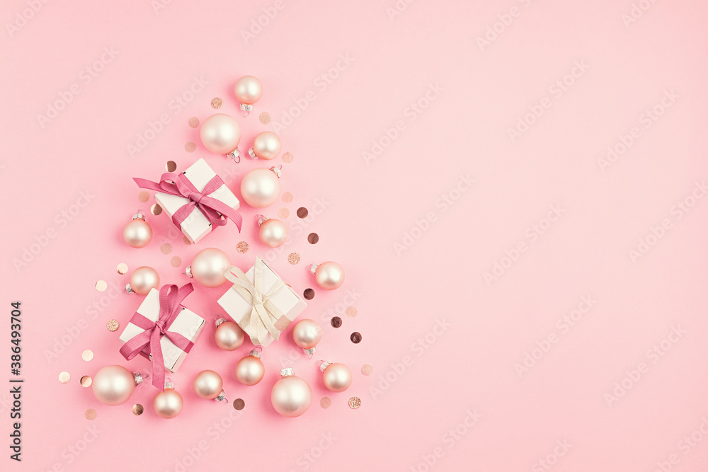 Christmas ornamets and gift boxes laid out in shape of Christmas tree on pink background Christmas ornamets and gift boxes laid out in shape of Christmas tree on pink background